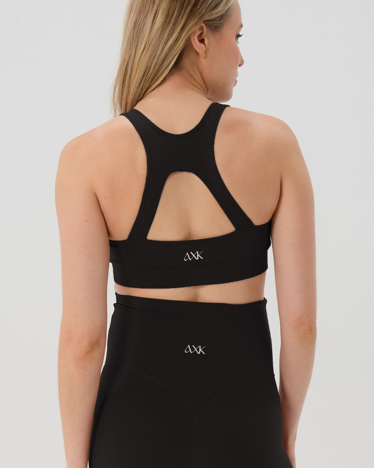 Pregnant woman wearing premium black high-impact, racerback maternity and nursing sports bra, with matching light gray maternity legging in a stylish set. Premium maternity athletic and activewear by AXK - high quality petite, tall, and plus size maternity.