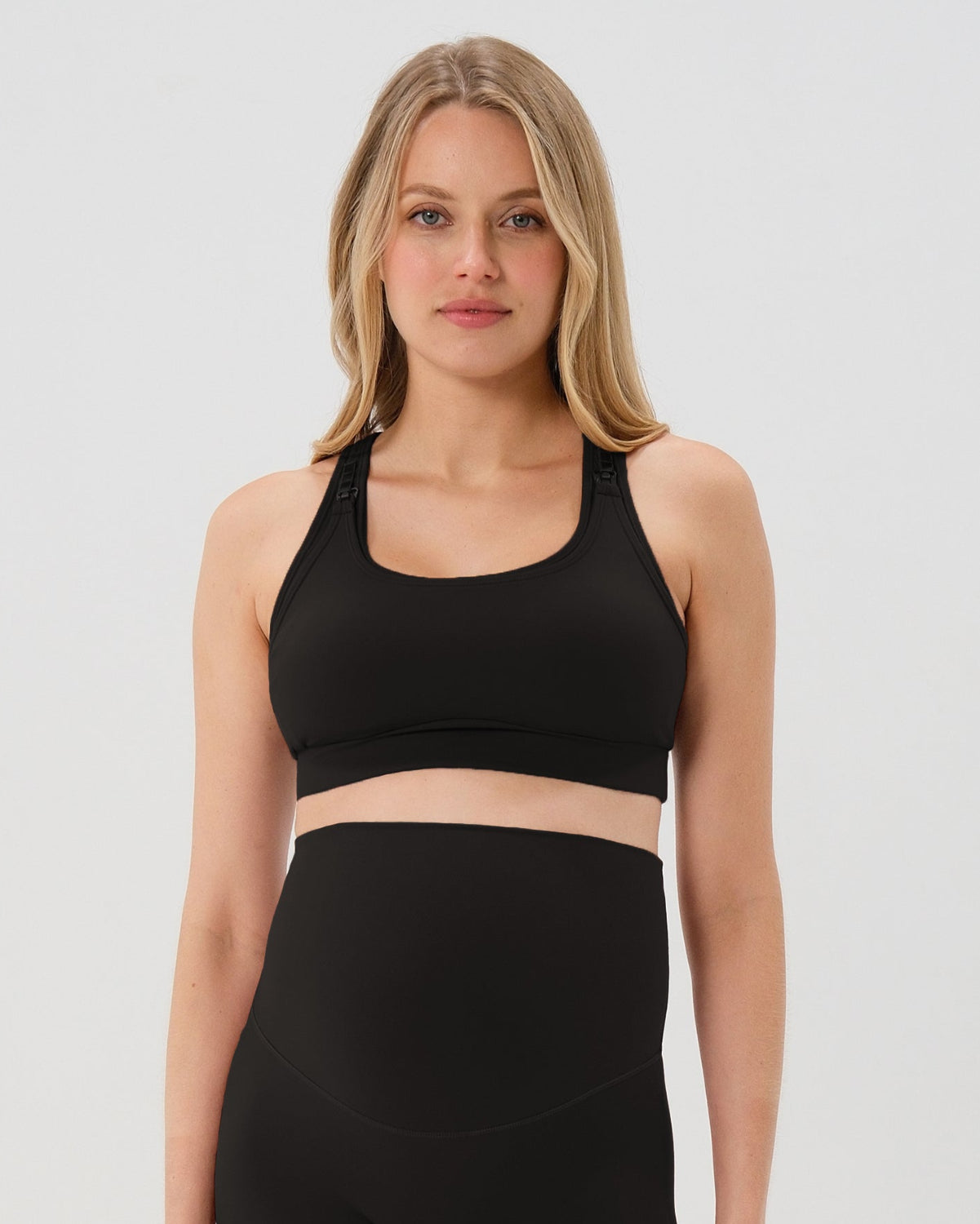 Pregnant woman wearing premium black high-impact, racerback maternity and nursing sports bra, with matching light gray maternity legging in a stylish set. Premium maternity athletic and activewear by AXK - high quality petite, tall, and plus size maternity. 