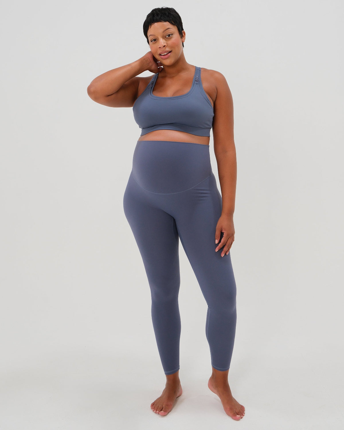Pregnant woman wearing our best reviewed premium black maternity leggings for 2026 with a matching trendy one shoulder nursing sports bra. Premium maternity athletic and activewear by AXK, available in plus sizes. Petite and tall friendly. 