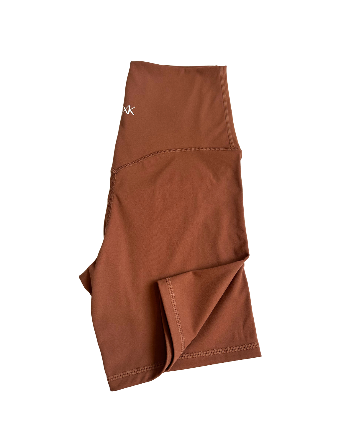 Flat lay of premium brown maternity bike shorts with a supportive high waist and AXK logo detail, displayed on a white background. Premium maternity athletic and activewear by AXK.
